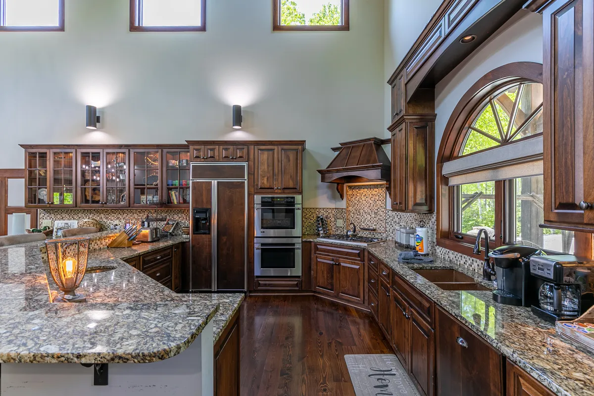 A modern kitchen scene featuring a gleaming granite countertop, sleek wood cabinetry, and an arched window that lets in natural light. Modern appliances are visible, reinforcing the kitchen's gourmet status. The setting feels both functional and stylish, ideal for preparing feasts or casual breakfasts.